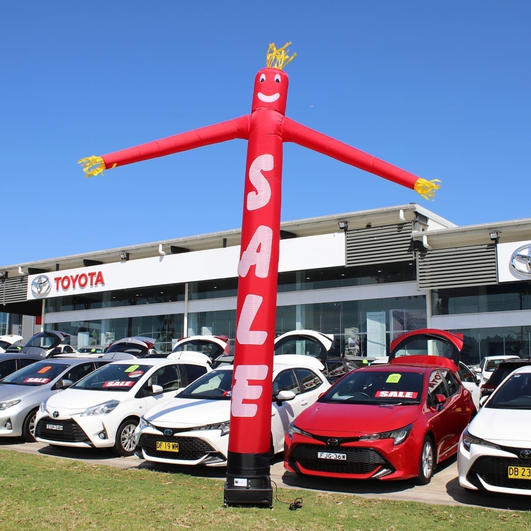 112SARW1 Red inflatable advertising man waving in front of Toyota car dealership.