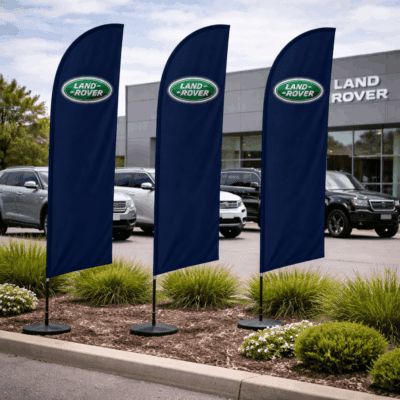 Land Rover flags displayed outside a dealership, featuring the Land Rover logo, set in a landscaped area with vehicles in the background.