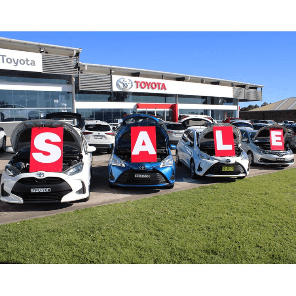 Under Bonnet SALE Set Cars displayed in front of a Toyota dealership with large red "SALE" letters on the hoods, promoting vehicle marketing and visibility for dealership sales.